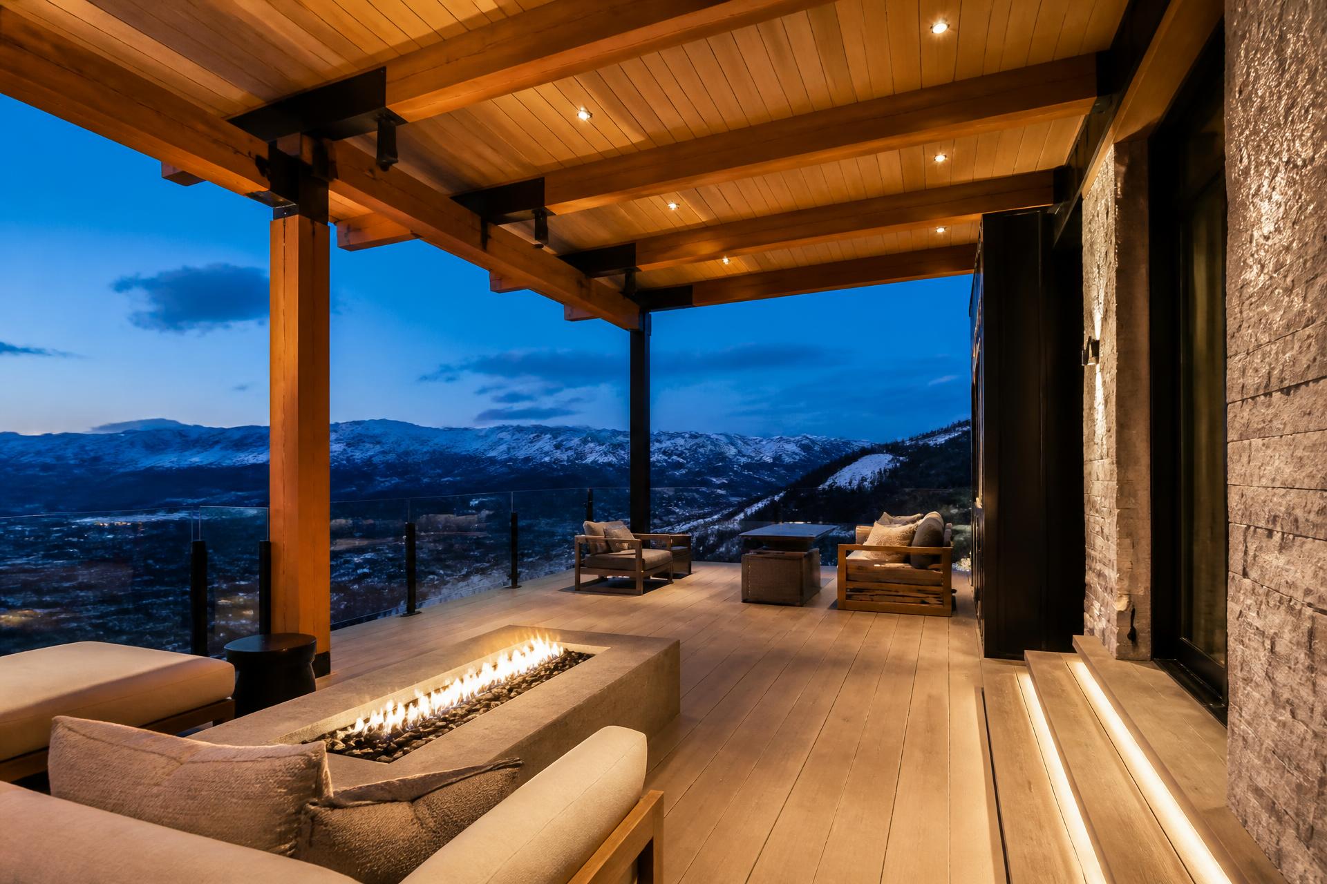 Covered mountain-modern deck in Utah with exposed timber roof structure, integrated lighting, and open mountain view at dusk